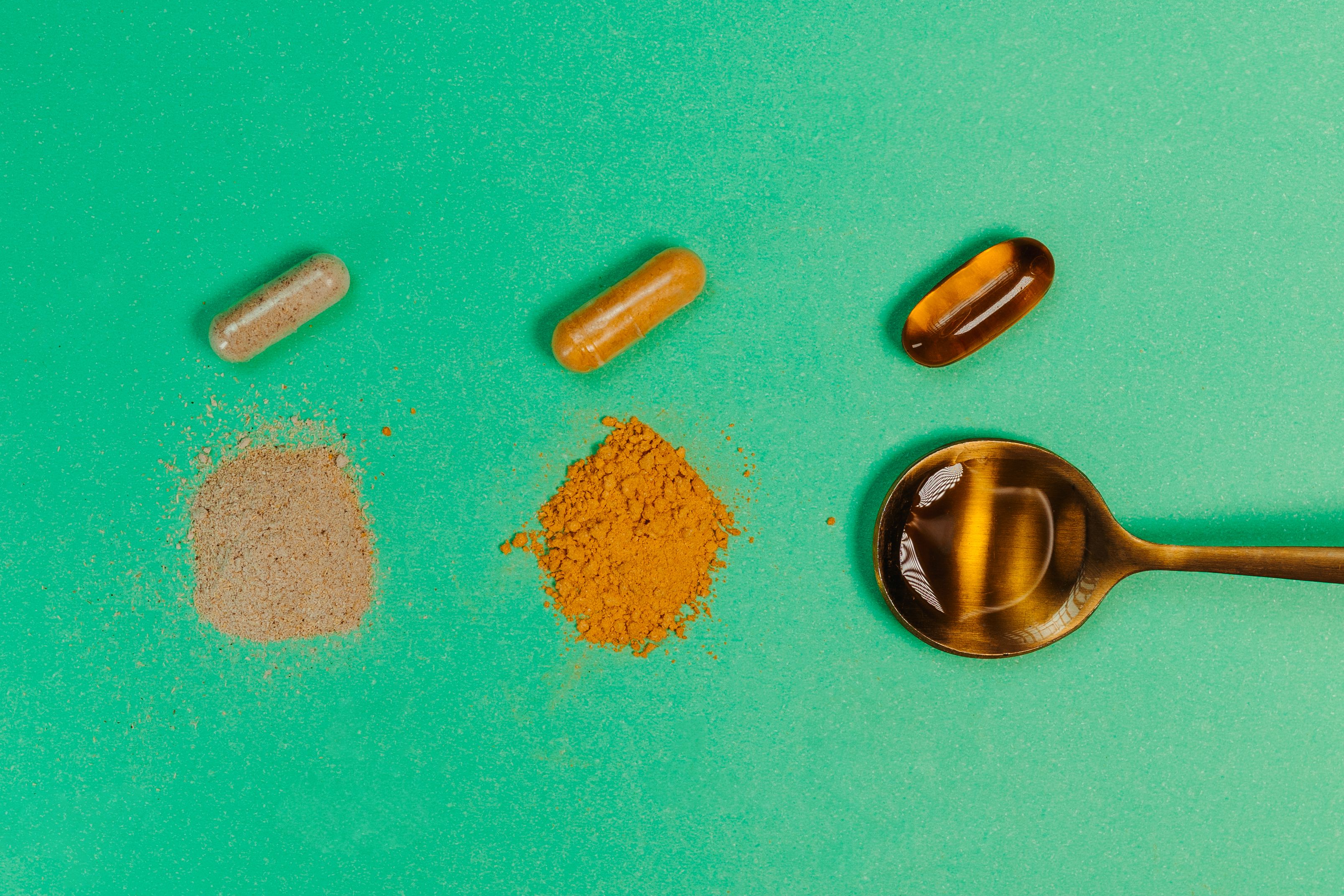 Golden spoon with pills and tablets on green background - Proprietary ingredients